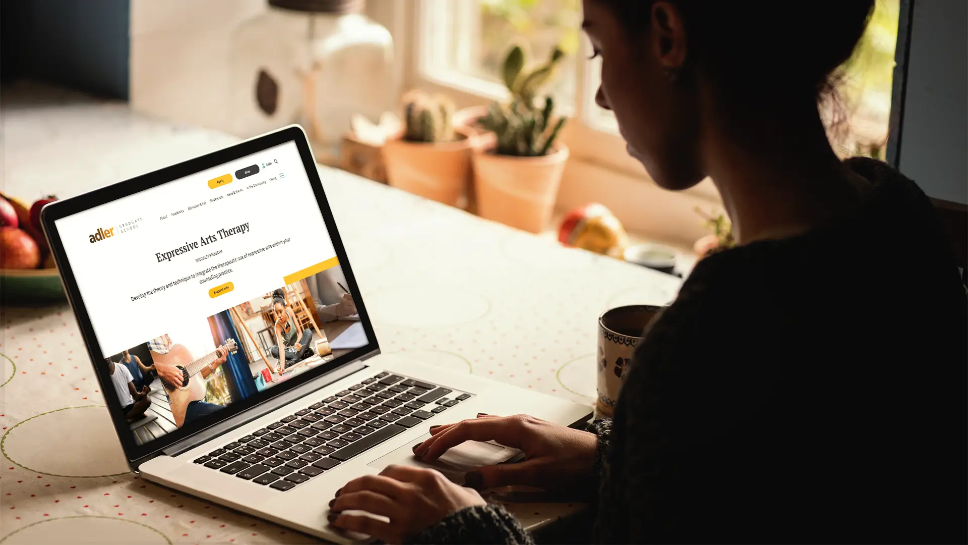Closeup photo of a person using a laptop with the new Adler Graduate School website displayed on the screen.